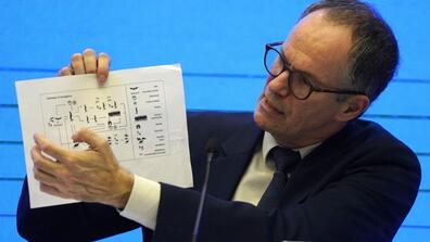 Peter Ben Embarek of the World Health Organization team holds up a chart showing pathways of transmission of the virus