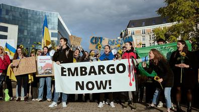 Protesters in May at Schuman Square in Brussels pushing for a total ban on Russian energy. The woman shouting into a megaphone is Dominika Lasota, who has emerged as a protest leader. / Ksenia Kuleshova for The New York Times