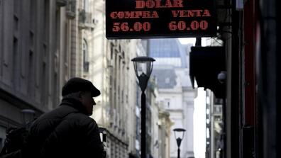 A man looks at a currency exchange board in Buenos Aires, Argentina, Monday, Aug. 12, 2019. Argentine stocks and currency plummeted on Monday after Argentine President Mauricio Macri was snubbed by voters who appeared to hand a resounding primary victory 