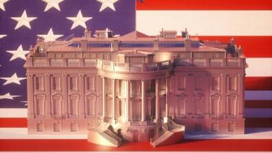 A model of the White House in front of the American flag