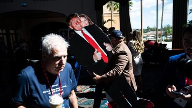 A man carries cardboard cutouts of former president Donald Trump and first lady Melania Trump during the first day of the Conservative Political Action Conference on Feb. 24 in Orlando.
