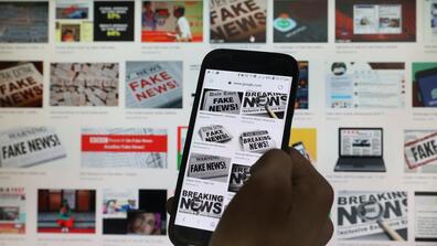 A computer screen and a phone screen, both showing images that say "Fake News"