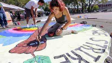 Sima Nisenbaum, 16, of Queens, paints a banner for the Sept. 20 climate strike at a lead up event at Thomas Greene Park on Sunday.