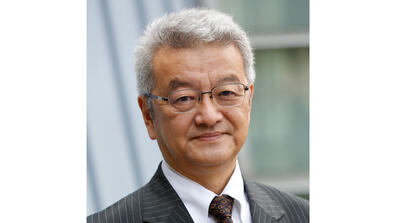 Takatoshi Ito is a middle-aged Japanese man with short gray hair and glasses; in this photo he's wearing a dark pinstriped suit