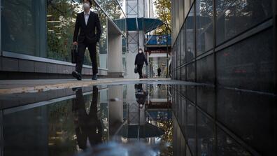 people walk down a narrow street after a rain